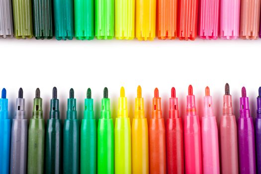Closeup view of a row of colorful felt tip pens over white background