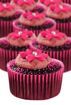 Delicious chocolate cupcakes in pink cups with flowers on top