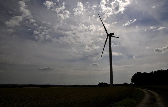 Silhouette of a wind turbine in the countryside with a cloudy sky