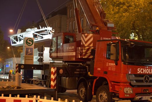 STUTTGART - OCTOBER 25: A truck-mounted crane is lifting a part of the old escalator as workers are installing a new one during renovation works in the metropolitan railway station Schwabstraße in the late evening of October 25, 2012 in Stuttgart, Germany