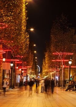 Night blured image of people walking on the famous boulevard Champs-Elysees in Paris during the winter holidays.