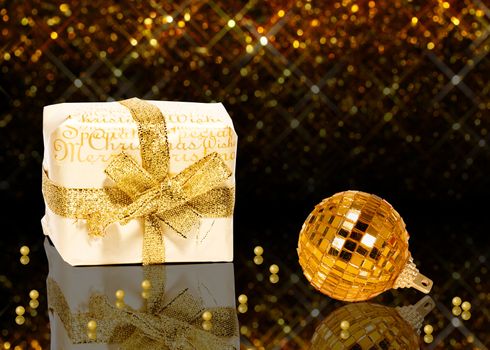 A glamourous golden Christmas illustration: A white gift box with golden christmas wishes, a golden Christmas ball and
golden pearls on a noble dark and golden bokeh background.