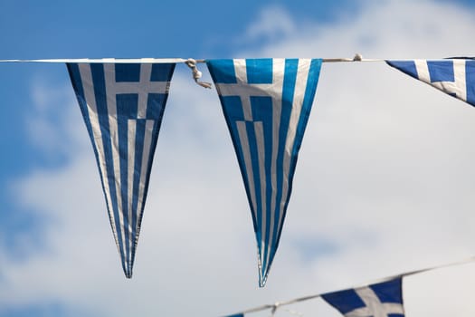 Triangular pennants of the Greek flag on a blue sky