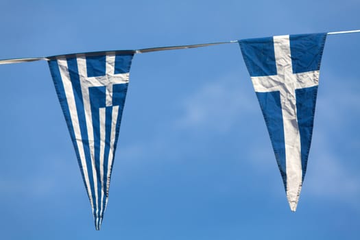 Triangular pennants of the Greek flag on a blue sky