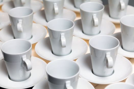 Many white coffee mugs in a line over a buffet