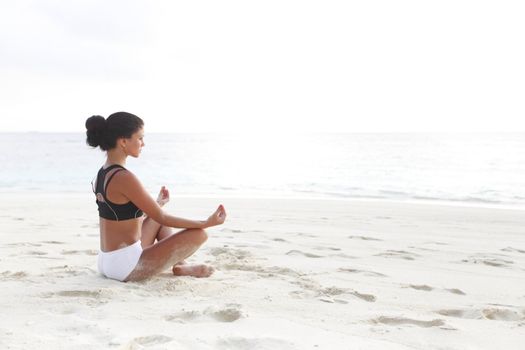 Yoga woman meditating on beach in the morning