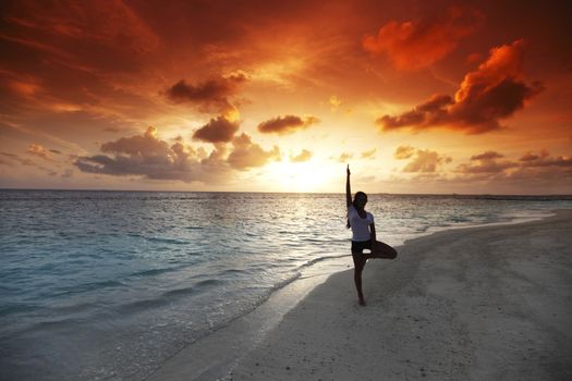 Beautiful yoga woman on beach at sunset