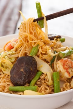 Spicy asian curry noodles with vegetables shrimps and china mushrooms on wooden table