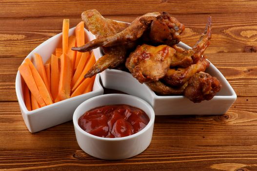 Chicken Wings, Carrot Sticks and Barbecue Dressing in White Bowls on Wood background