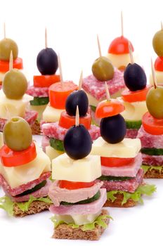 Arrangement of Appetizers with Bacon, Salami, Tomatoes, Cheese, Cucumber, Green Olive, Black Olive, Lettuce and Whole Grain Bread isolated on white background