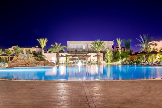 A clear blue swimming pool in a beautiful setting during the night