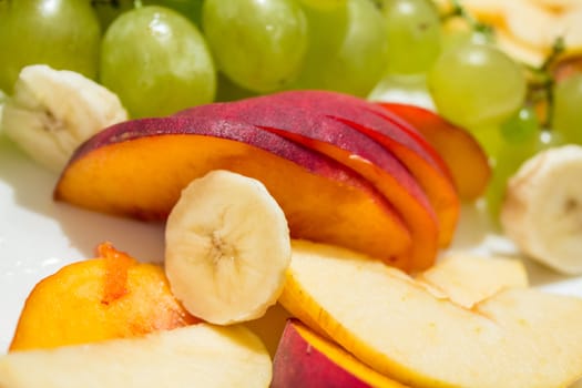 A plate filled with ripe and tasty peaches, banana and grapes