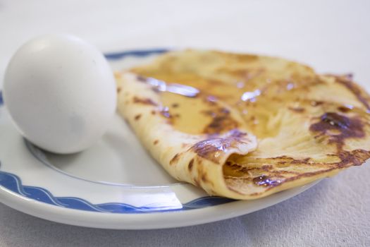 Breakfast comprising of boiled eggs and pancake drenched with syrup