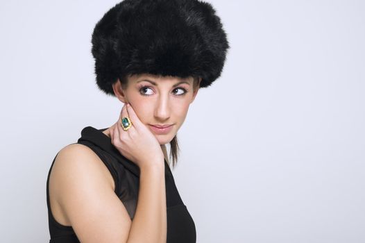 Head and shoulders portrait of a beautiful slender sophisticated woman modeling a winter fur hat against a white studio background with copy space