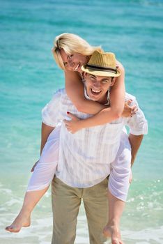 Happy young couple on tropical beach with blue sea on background