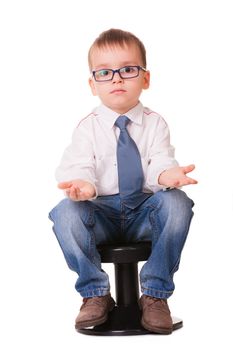 Confused clever kid in jeans and shirt sitting on small chair isolated on white background