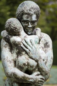 Close view of an old stone statue of a woman holding a child.