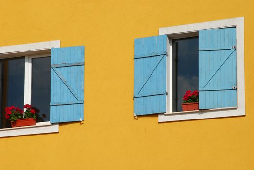 Orange house wall, two windows, blue shutters