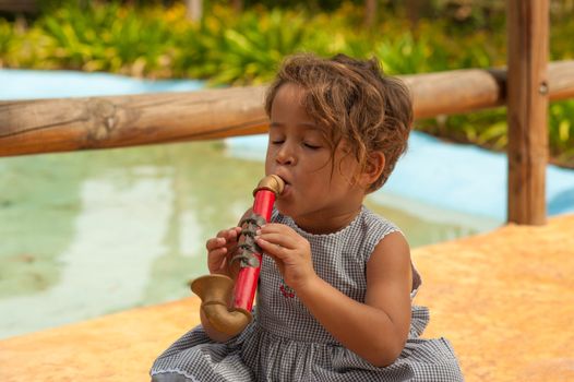 Cute Hispanic girl playing with a toy saxophone