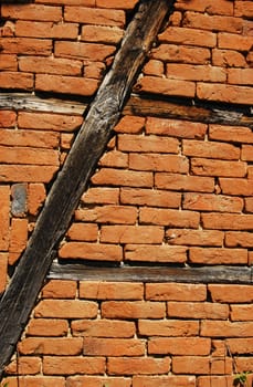 Old frame-build half-timbered red bricks barn's wall vertical