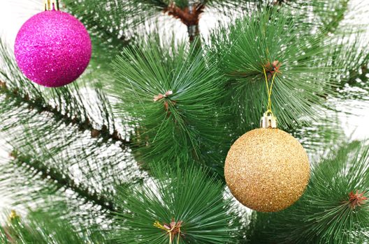 Detail of plastic Christmas tree with hanged shiny baubles