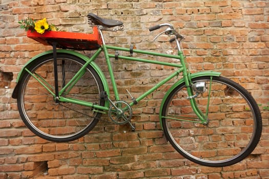 Green bicycle hung as decoration on the wall.