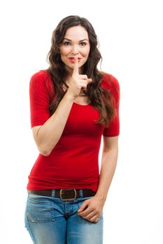 A beautiful smiling  woman in red top doing silence sign with her finger to her mouth.  Isolated on white.