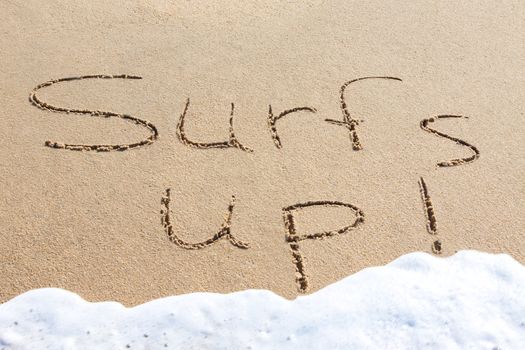 Surf's up - written in the sand with a foamy wave underneath