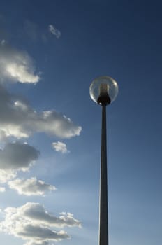 Modern spherical street light against a cloudy dramatic blue sky