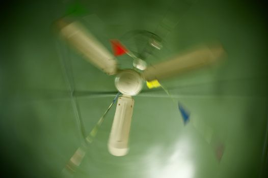 Old ceiling fan spinning in a cafe ceiling decorated with colorful bunting