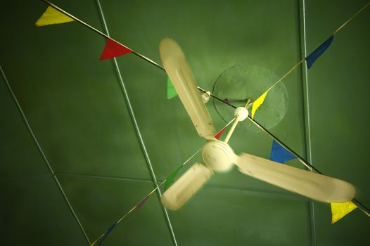 Old ceiling fan spinning in a cafe ceiling decorated with colorful bunting
