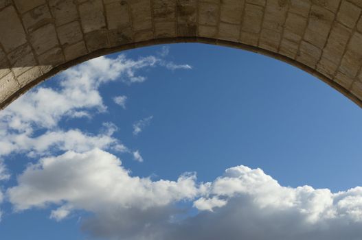 View of the sky with clouds through an old stone archway