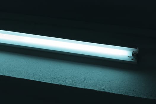 Detail of a fluorescent tube mounted on a wall, false green color light