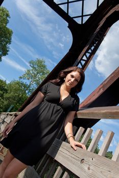 A carefree brunette woman hanging out along an old rusted walking bridge.
