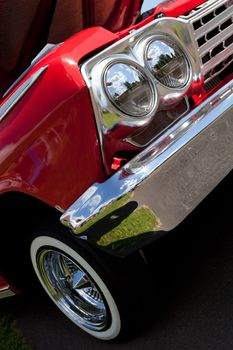 A closeup of the headlights and front bumper on a vintage American automobile.