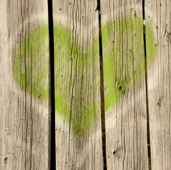 Green grafitti heart on old wood background