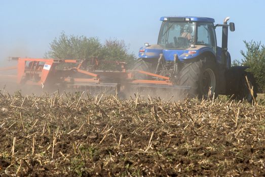 Fall harrowing with tractor and harrow on field closeup