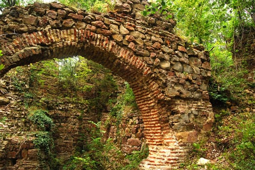 Ancient roman Balkan fortress arch gate ruins in forest