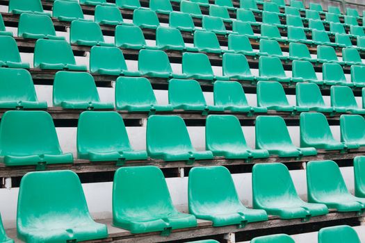 Green plastic old chairs in stadium