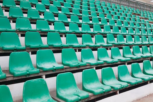 Green plastic old chairs in stadium