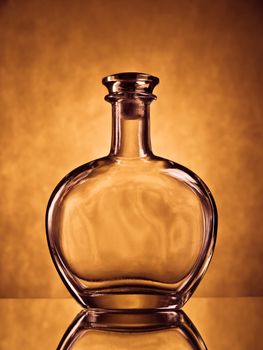 Empty round cognac bottle on brown grunge background