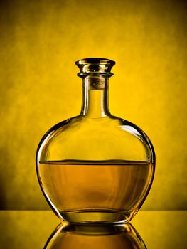 Round elegant bottle of cognac on yellow background