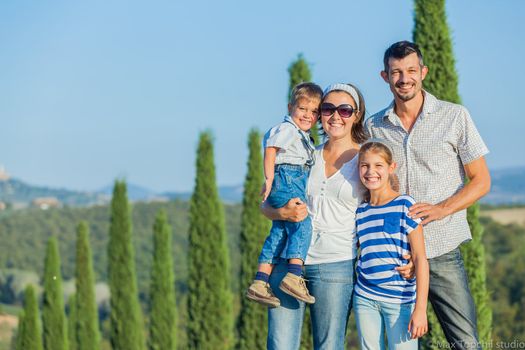 Happy family having fun on vacations in Tuscan against cypress alley background