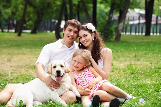 Young Family Outdoors in summer park with a dog