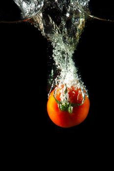 fresh tomato uder water on black background