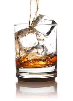Pouring whiskey in glass with ice isolated on white