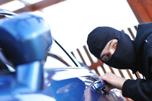 Young man in mask trying to steal a car