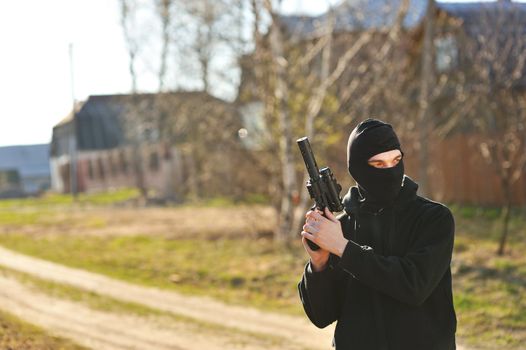 Gunman in black mask holding gun with silencer