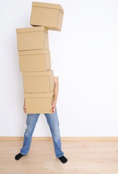 Young man carrying and dropping his stack of moving boxes