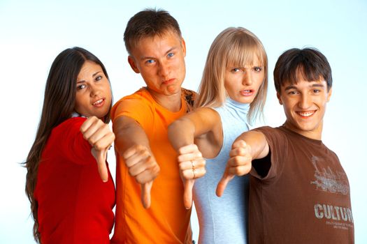 Four young people on white background and giving the thumbs-down sign. 